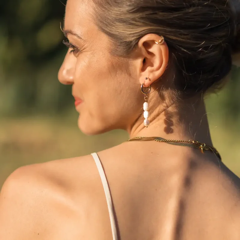 Boucle d'oreille pendante perles d'eau douce - Aura Une femme qui porte une boucle d'oreille pendante en perle d'eau douce. Aura un bijou fait main par DENADDA.